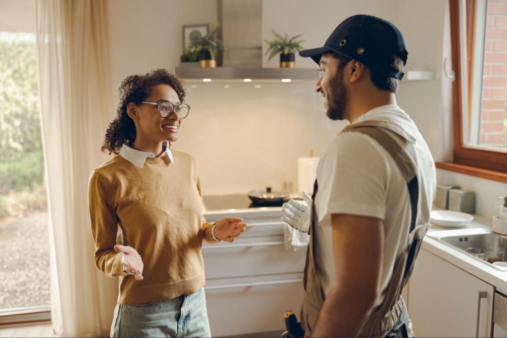 Repair man speaking to a woman in a house.