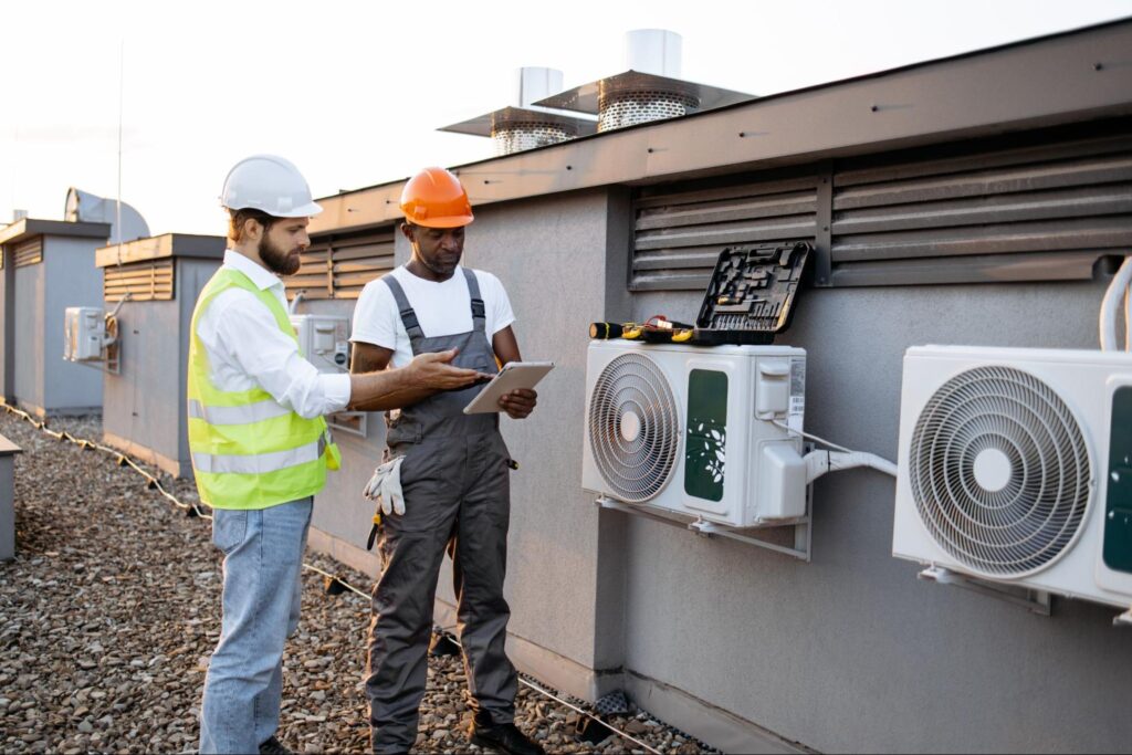 Two building employees perform quarterly AC system maintenance.