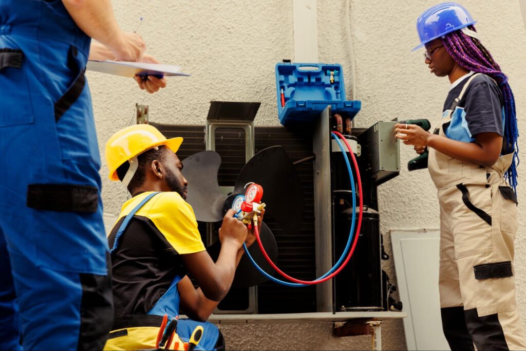 Three AC technicians refill the freon in the AC.