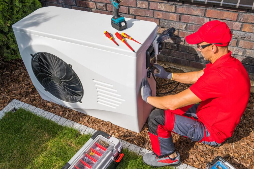 A technician repairing a heating unit outside of a building.