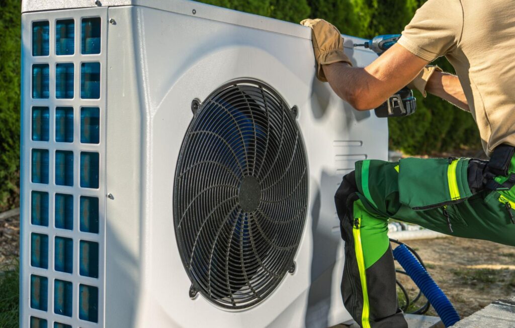 An HVAC technician repairing a heating unit outdoors.
