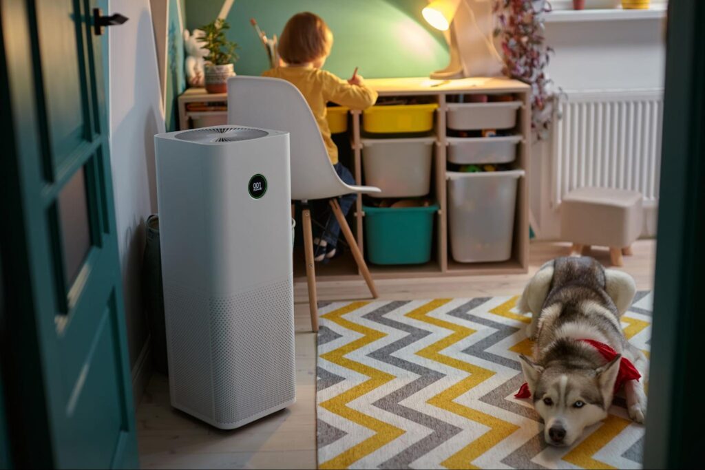A child working on his desk in his room with an air purification system behind him.