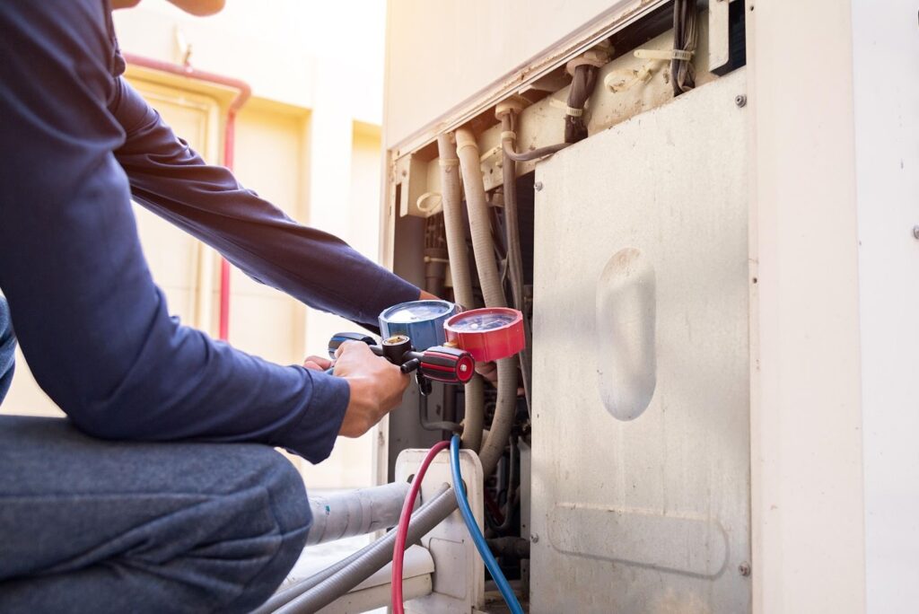 HVAC specialist inspecting an air conditioning unit with a diagnostic gauge